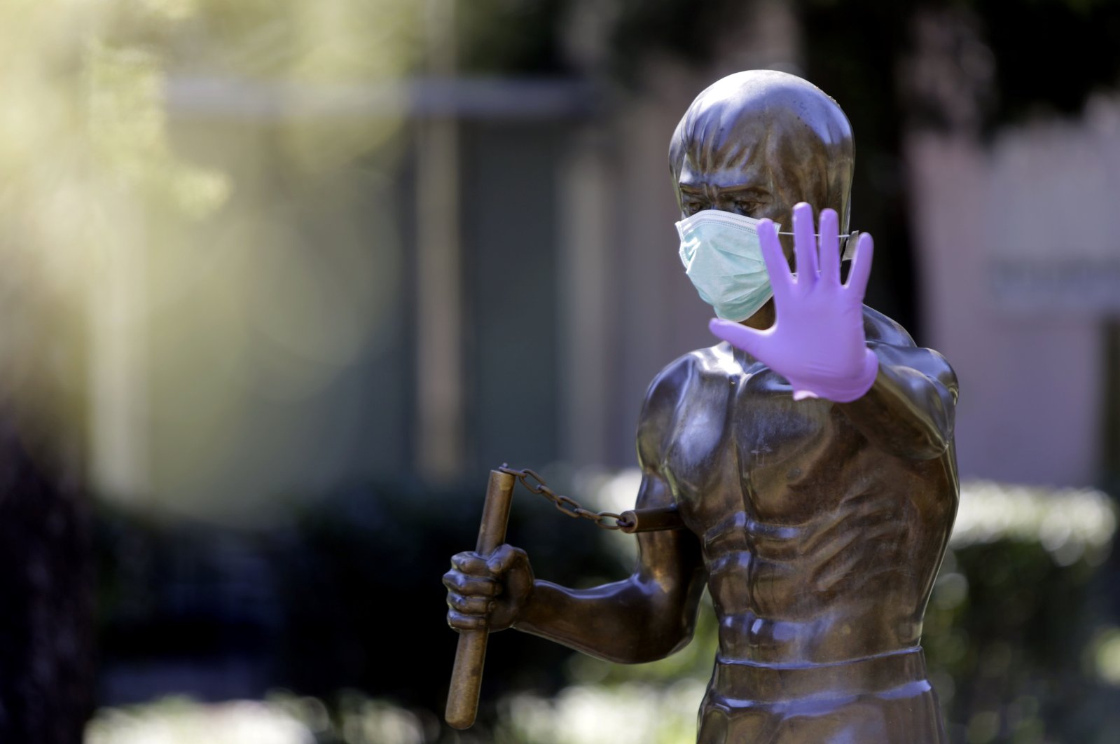 The statue dedicated to martial arts icon and actor Bruce Lee, wearing surgical gloves and a face mask, in the central park of Mostar, Bosnia-Herzegovina, April 2, 2020. (Photo by STR / AFP)