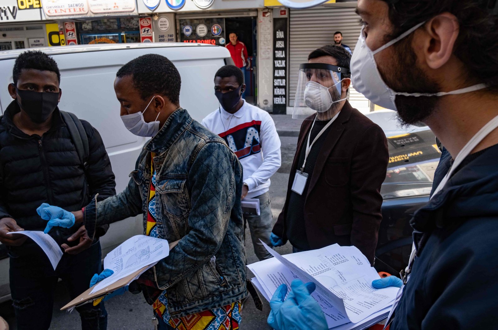 Members of a solidarity network hand out disinfectant, gloves and face masks as well as food cards to African migrants in Istanbul, April 17, 2020. (AFP Photo)