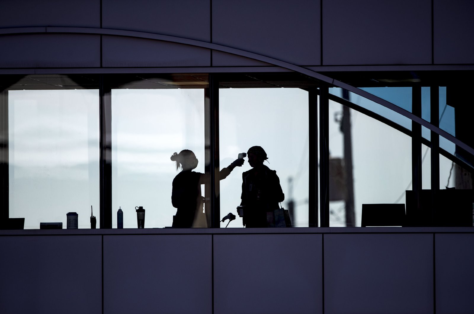 Amid coronavirus concerns, a health care worker takes the temperature of a visitor at Essentia Health who was crossing over a skywalk bridge from the adjoining parking deck in Duluth, Minnesota, April 10, 2020. (AP Photo)
