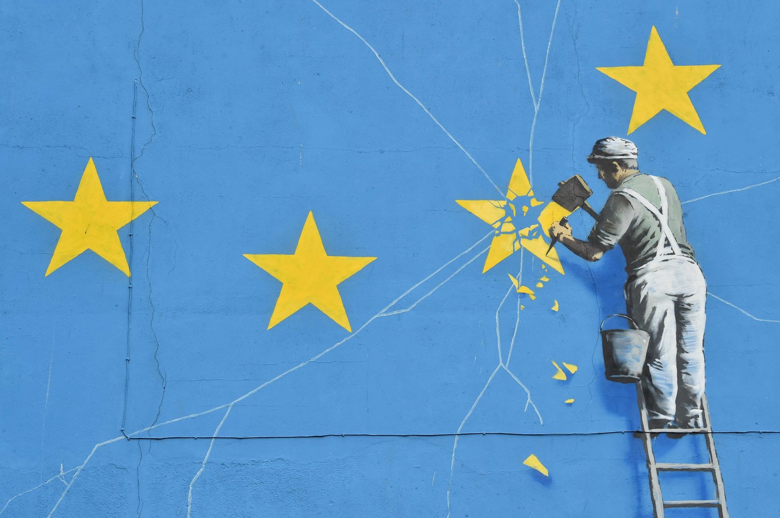  This file photo taken on January 7, 2019 shows a mural by British artist Banksy, depicting a workman chipping away at one of the stars on a European Union (EU) themed flag,in Dover, south east England. - Britain leaves the European Union on January 31, ending more than four decades of economic, political and legal integration with its closest neighbours. (Photo by Glyn KIRK / AFP)