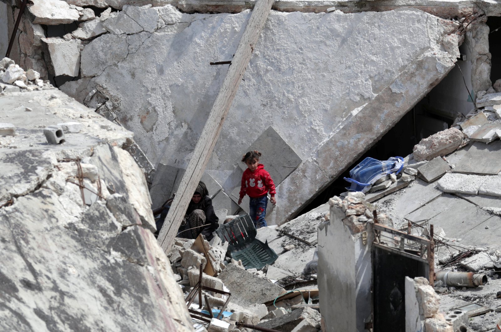 A girl stands near a woman on the rubble of a damaged building in the opposition-held town of Nairab, in northwest Syria’s Idlib region, Syria April 17, 2020. REUTERS