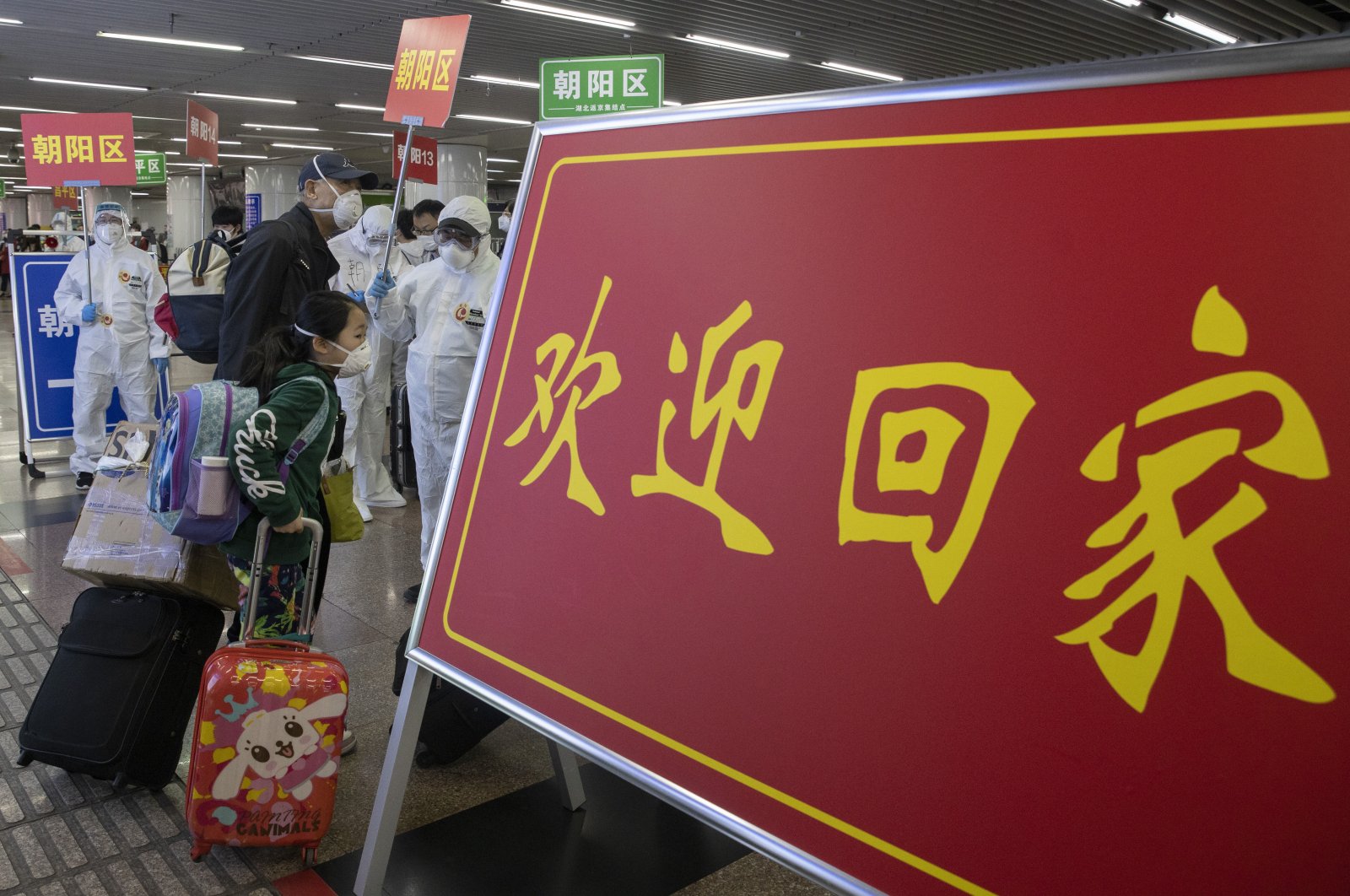 Passengers from Wuhan walk past a sign which reads "Welcome Home" after arriving on a high-speed train in Beijing, China, April 19, 2020. (AP Photo)