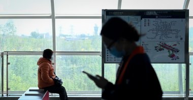 A woman (L) wearing a face mask sits on a bench at a subway station in Beijing on April 21, 2020. (AFP Photo)