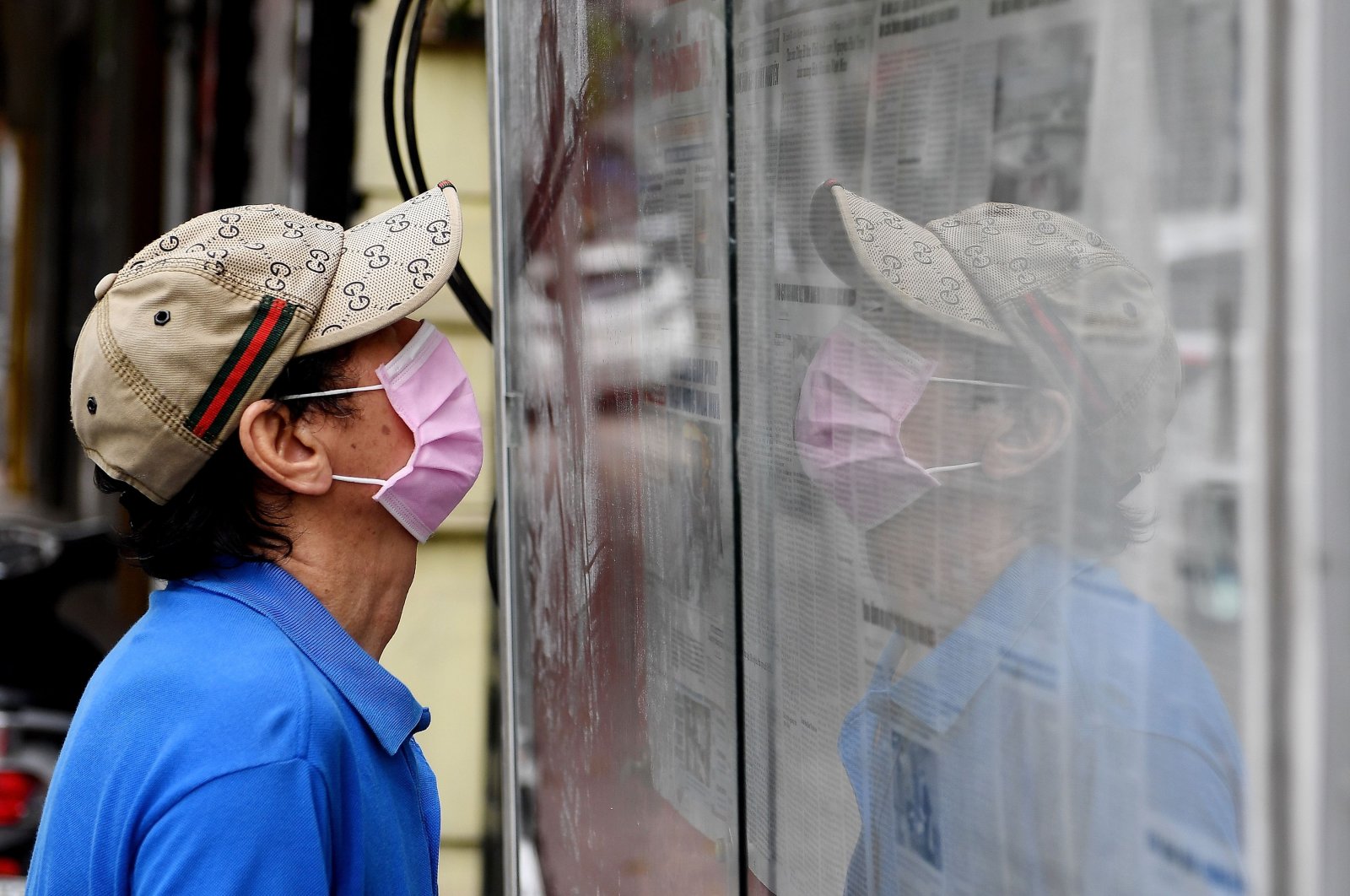 A man wearing a face mask reads the local daily newspaper "Hanoi Moi" displayed in a case on a street amid Vietnam's nationwide social isolation effort as a preventive measure against the spread of the COVID-19 coronavirus in Hanoi on April 21, 2020. (AFP Photo)