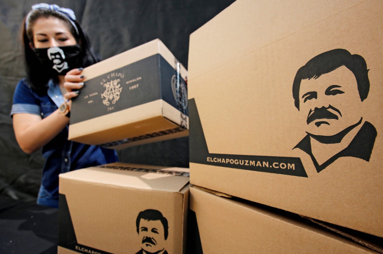 An employee of the Alejandrina Guzman Foundation wears a face mask with the image of Mexican drug lord Joaquin "El Chapo" Guzman -Alejandrina's father- as she arranges boxes with basic goods to be donated to people in need amid the new coronavirus pandemic in Guadalajara, Mexico, on April 17, 2020. (AFP Photo)