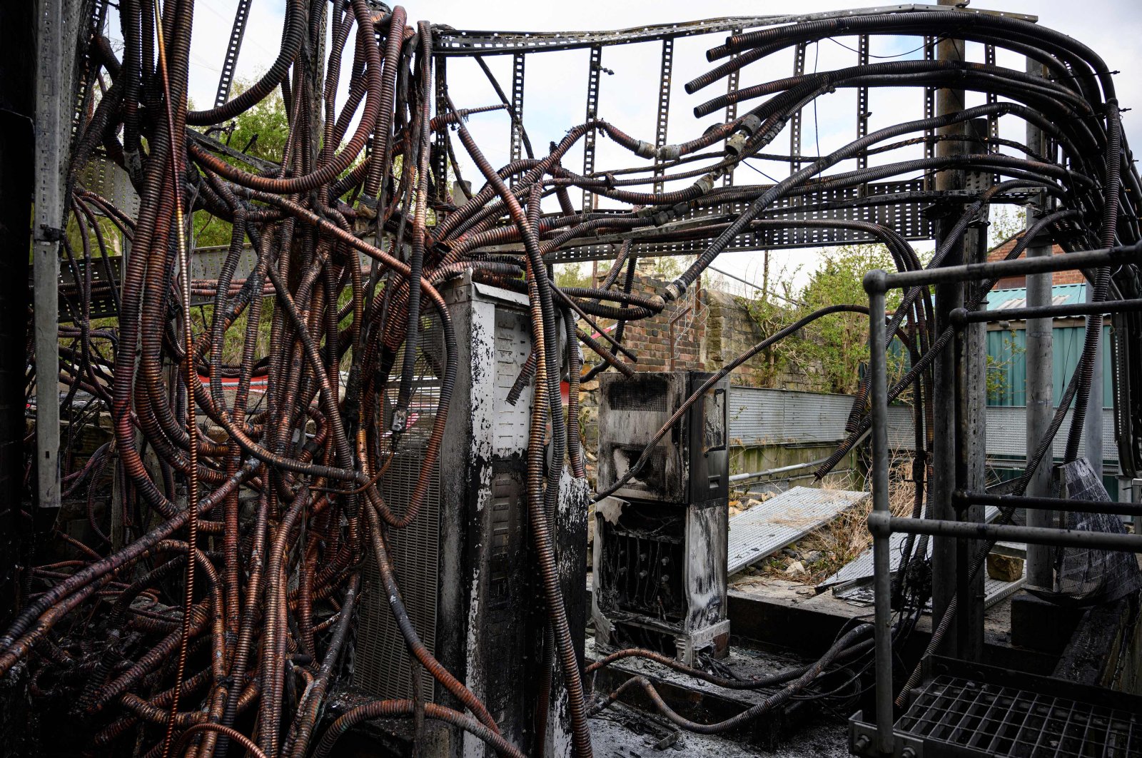 Damaged cabling and telecommunications equipment is pictured following a fire at a phone mast, attatched to the chimney at the converted Fearnleys Mill residential apartment block complex in Huddersfield, northern England, on April 17, 2020. It is not yet known what caused the mast, which is attached to a chimney at the Fearnleys Mill development, to go up in flames. But the fire comes after a number of mobile phone masts have been set on fire amid claims of a link between 5G and the novel coronavirus COVID-19. (AFP Photo)