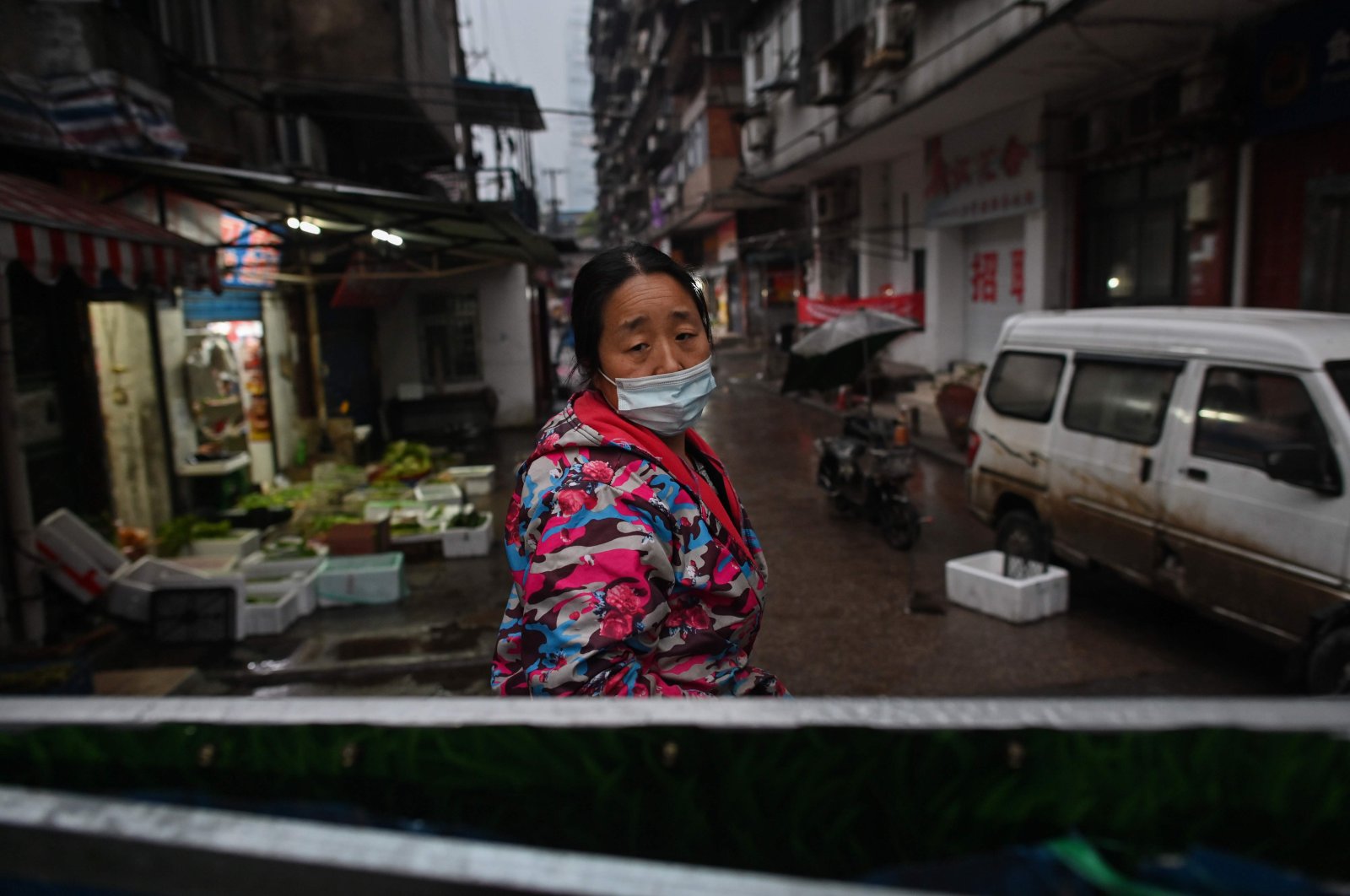 A woman, wearing a face mask as a preventive measure against the spread of the COVID-19 stands at an access to a neighborhood closed off by barriers in Wuhan, China's central Hubei province, Monday, April 20, 2020. (AFP Photo)