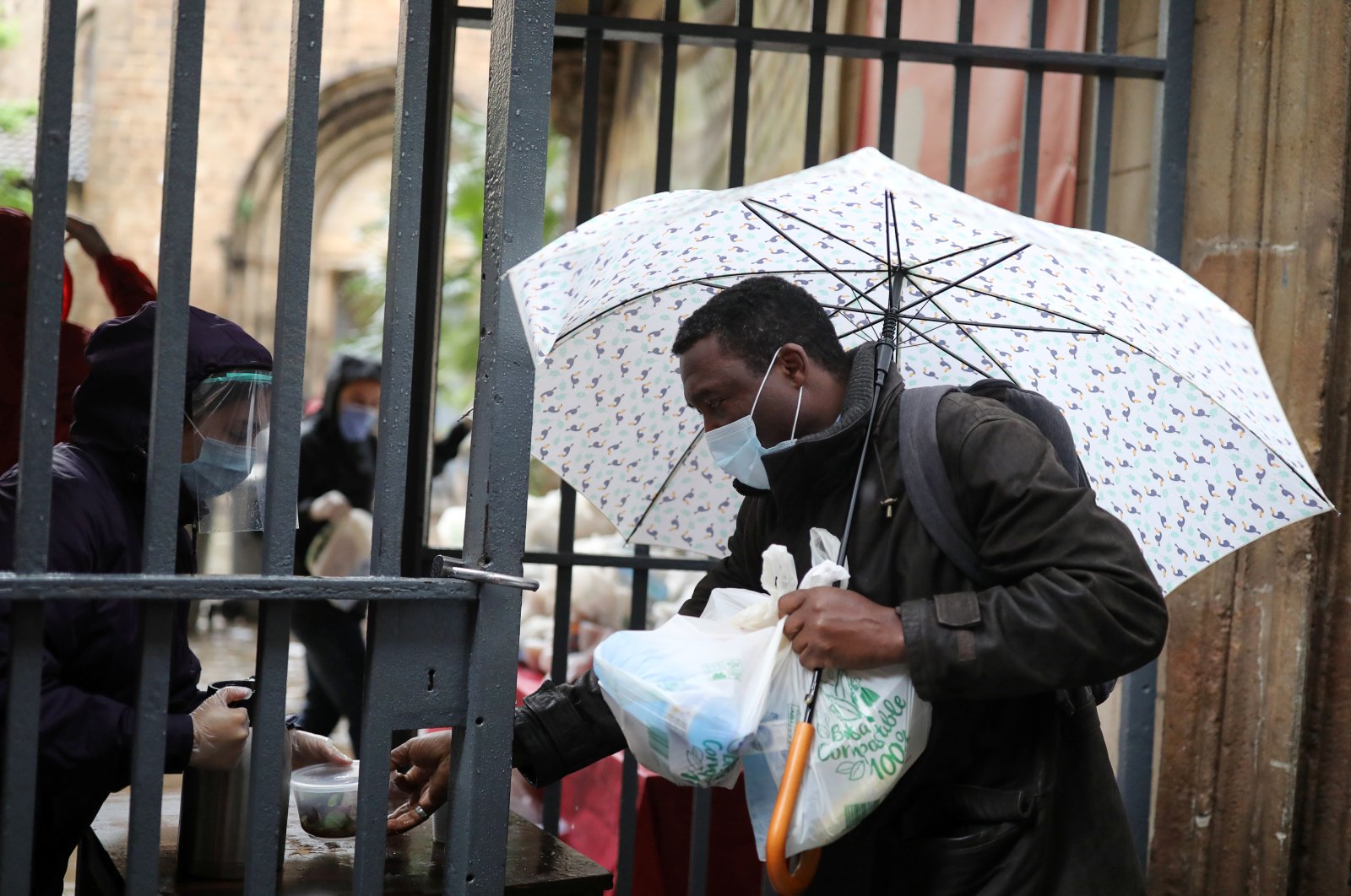Volunteers give free food packages for a man amid economic hardship outside parish church of Santa Anna, amid the spread of the coronavirus disease (COVID-19), in Barcelona, Spain, April 21, 2020. (Reuters Photo)