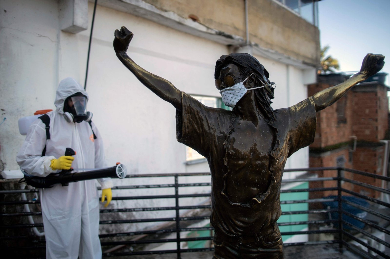 A volunteer disinfects the statue of US singer Michael Jackson, at the Santa Marta favela in Rio de Janeiro, Brazil, during the COVID-19 coronavirus pandemic on April 20, 2020. (AFP Photo)