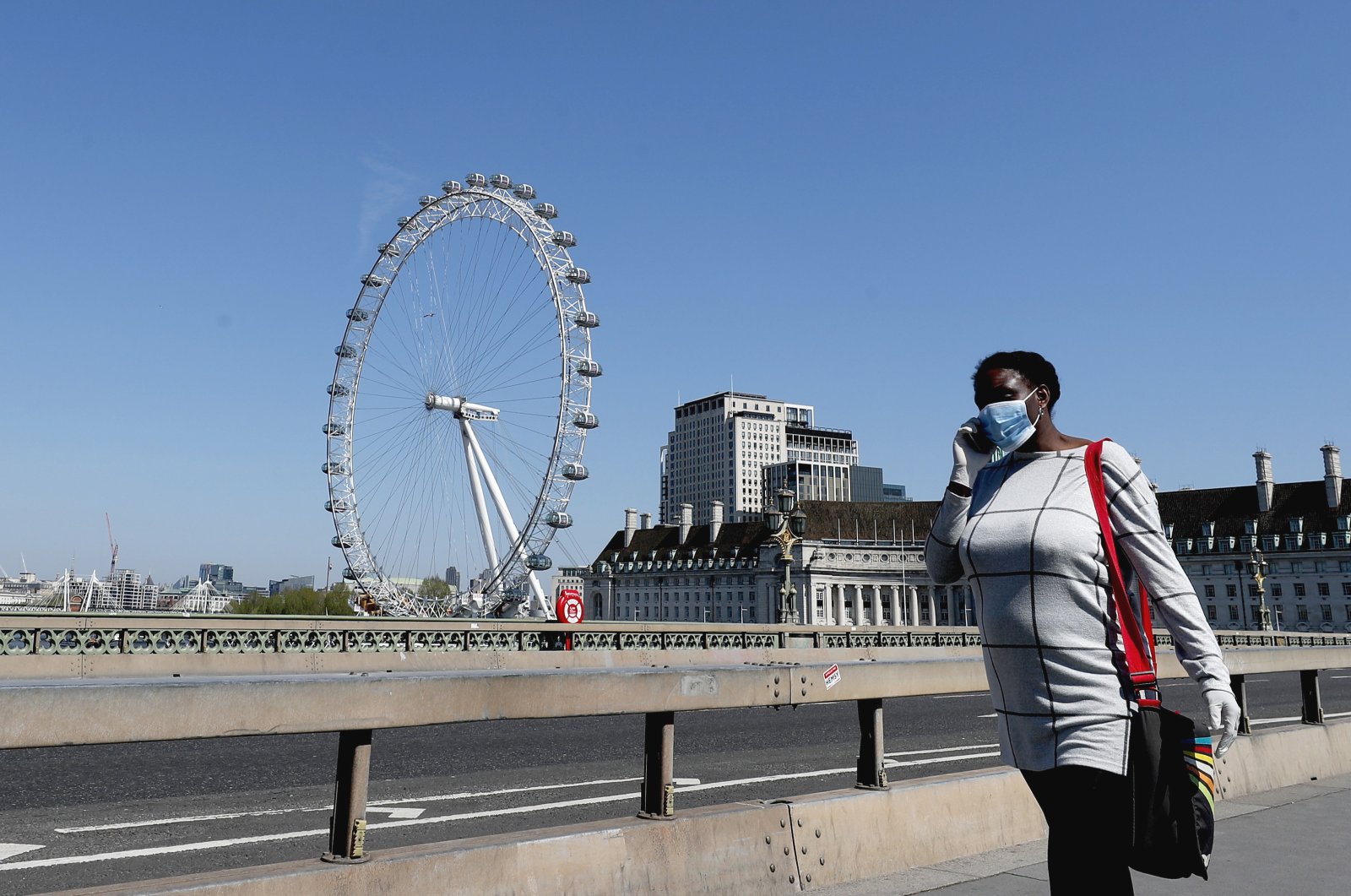 A woman wearing a protective mask walks over Westminster Bridge in London, England, April 22, 2020. (AP Photo)