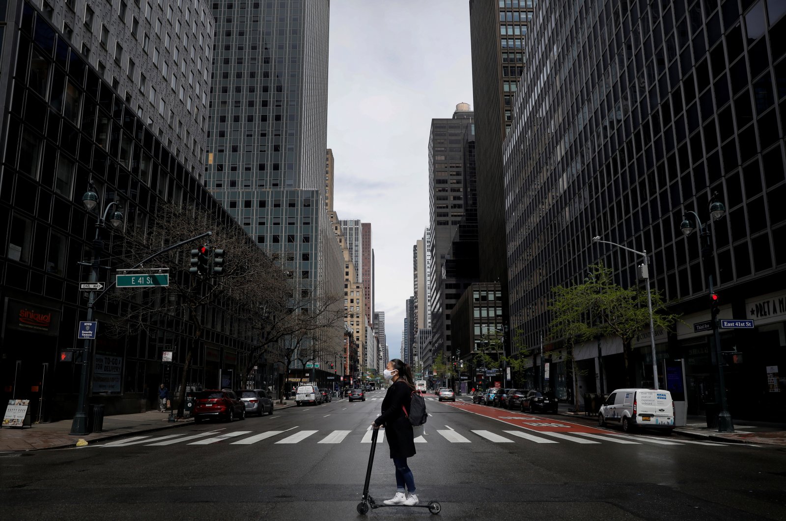 A woman wearing a protective face mask rides a scooter across a nearly empty 3rd Avenue in midtown Manhattan during the coronavirus outbreak, in New York City, New York, U.S., April 21, 2020. (Reuters Photo)