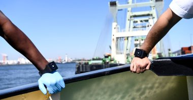 A Belgian deckhand and a captain wear Romware Covid Radius bracelets during a presentation of the device at the Port of Antwerp, on April 22, 2020. (AFP Photo)