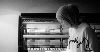 Büşra Kayıkçı poses with a music notebook in front of her piano. (Courtesy of Büşra Kayıkçı)