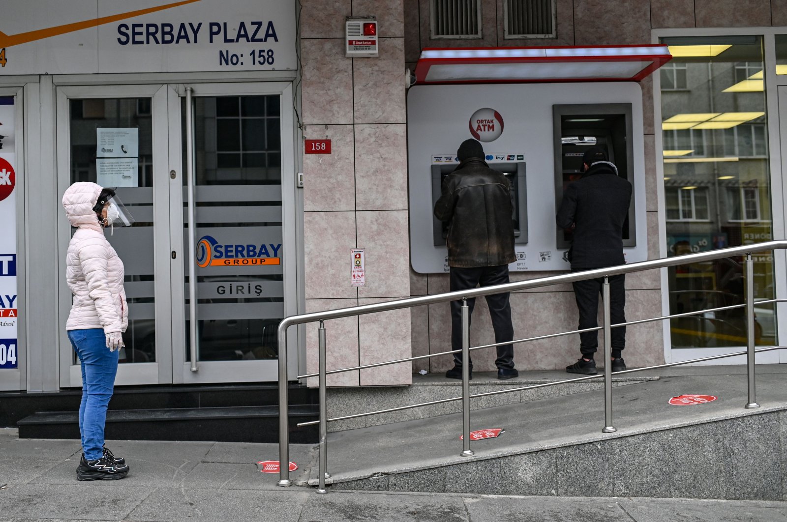 People queue to use ATM machines while observing social distancing rules outside a bank in Istanbul, Turkey, April 21, 2020. (AP Photo)