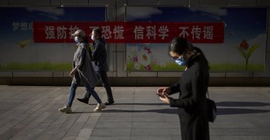 People wear face masks to protect against the spread of the new coronavirus as they walk along a street, Beijing, China, April 23, 2020. (AP Photo)