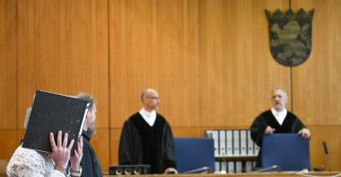 Defense lawyers Serkan Alkan (L) and Martin Heising (R) look at Taha al-Jumailly (hiding his face), who is believed to have belonged to the Daesh terrorist group, as judges arrive for the start of his trial for genocide and murdering a young Yazidi girl he held as a slave, at the Higher Regional Court (OLG) in Frankfurt, Germany, April 24, 2020. (AFP Photo)