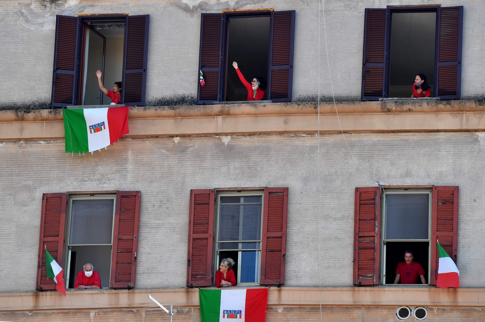 Residents with Italian flags sing Italian partizan song "Bella Ciao" in the Garbatella district of Rome, April 25, 2020. (AFP Photo)