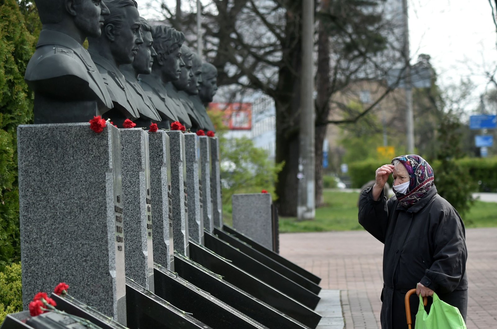 An elderly woman wearing a face mask crosses herself as she visits Chernobyl's memorial in Kiev to commemorate the victims on the 34th anniversary of the tragedy on April 26, 2020, amid the COVID-19 coronavirus pandemic. (AFP Photo) 
