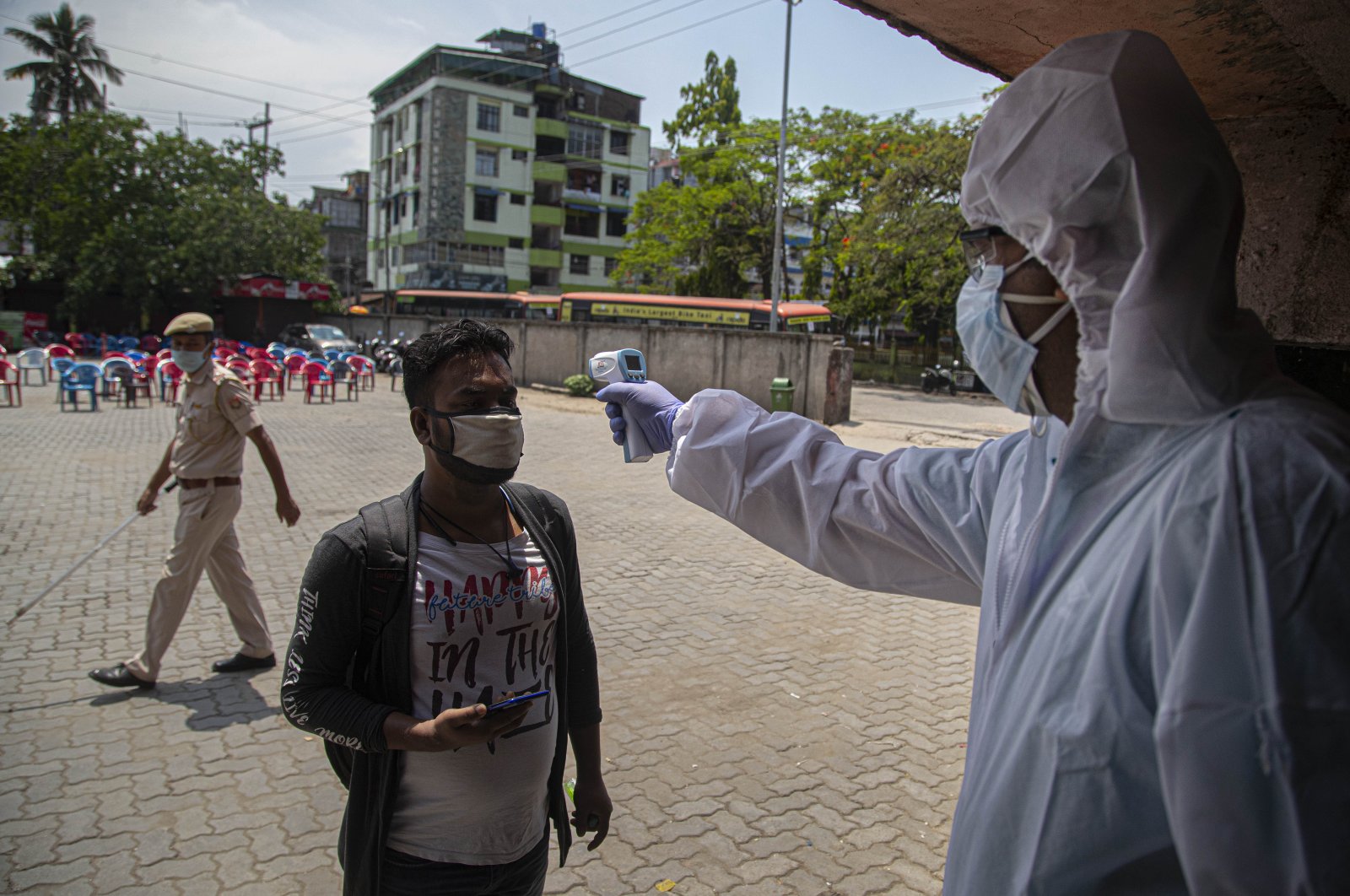 A health worker checks temperature of a passenger as people who were stranded in the city due to the month-long lockdown to curb the spread of new coronavirus, arrive to board special buses to their villages in Gauhati, India, April 27, 2020. (AP Photo)