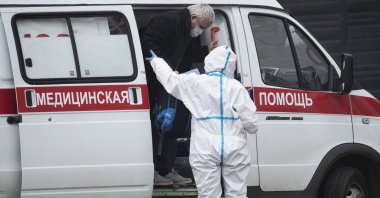 In this April 27, 2020, photo, a medical worker wearing protective gear helps a man, suspected of having the coronavirus infection, to get out from an ambulance at a hospital in Kommunarka, outside Moscow, Russia. (AP Photo)