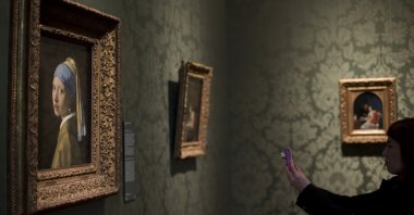 A visitor takes a picture of Johannes Vermeer's 17th century masterpiece "Girl with a Pearl Earring," (L) during a preview for the press of the renovated Mauritshuis in The Hague, the Netherlands, June 20, 2014. (AP Photo)