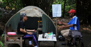 Abdullah Al Mabrur talks with his neighbour outside a tent he used for self-quarantine on a river bank after he came back from Pekanbaru, to prevent the spread of the coronavirus disease in Klaten, Central Java province, Indonesia, April 20, 2020. (Reuters Photo)