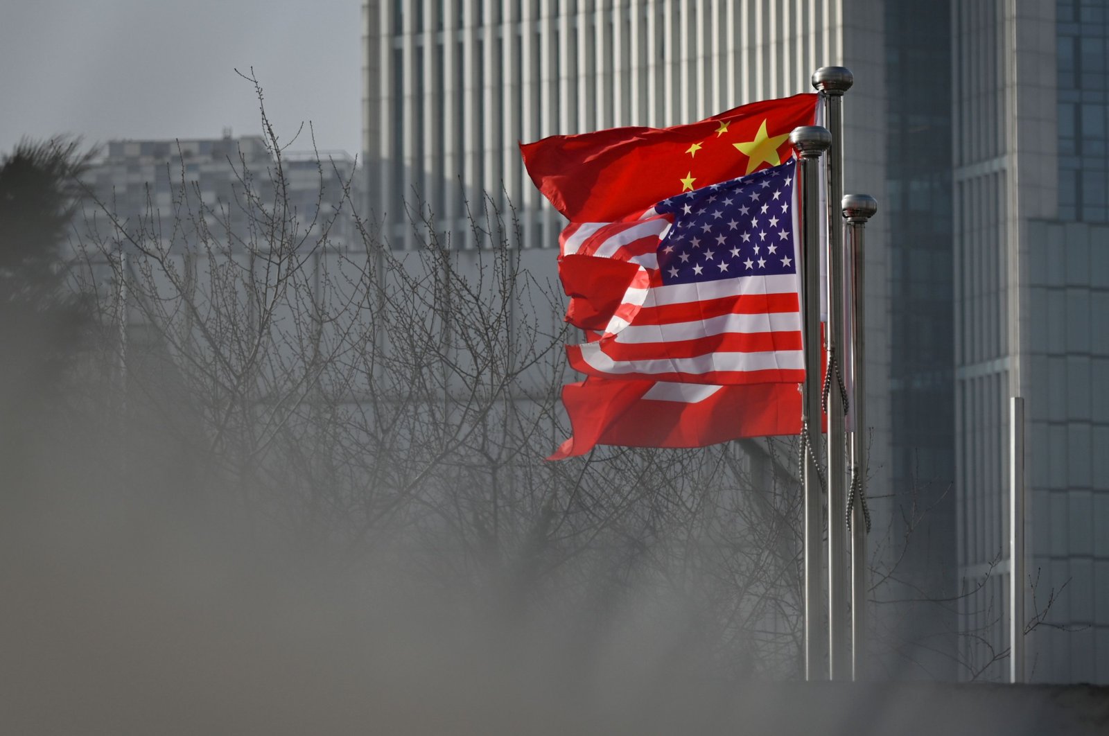 Chinese and U.S. national flags flutter at the entrance of a company office building in Beijing, China, Jan. 19, 2020. (AFP Photo)