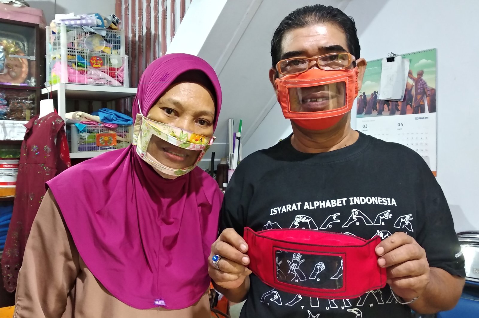 Imama Saroso (R) and his wife Faizah Badaruddin (L), who are hearing and speech-impaired, pose with homemade face masks which enable people with disabilities like them to read lips when communicating, in Makassar, South Sulawesi, April 28, 2020. (AFP Photo)