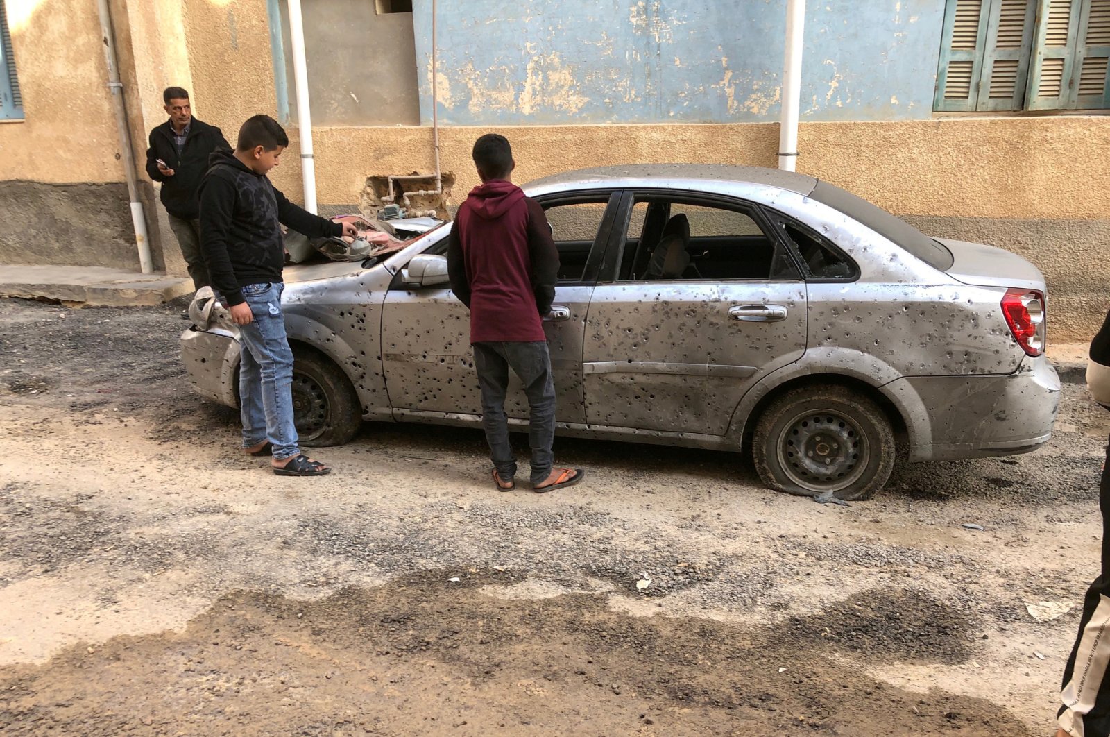 Libyan boys check a damaged car after a shell fell on a residential area of Hadba al-Badri district, in Tripoli, Libya, Jan. 28, 2020. (Reuters Photo)