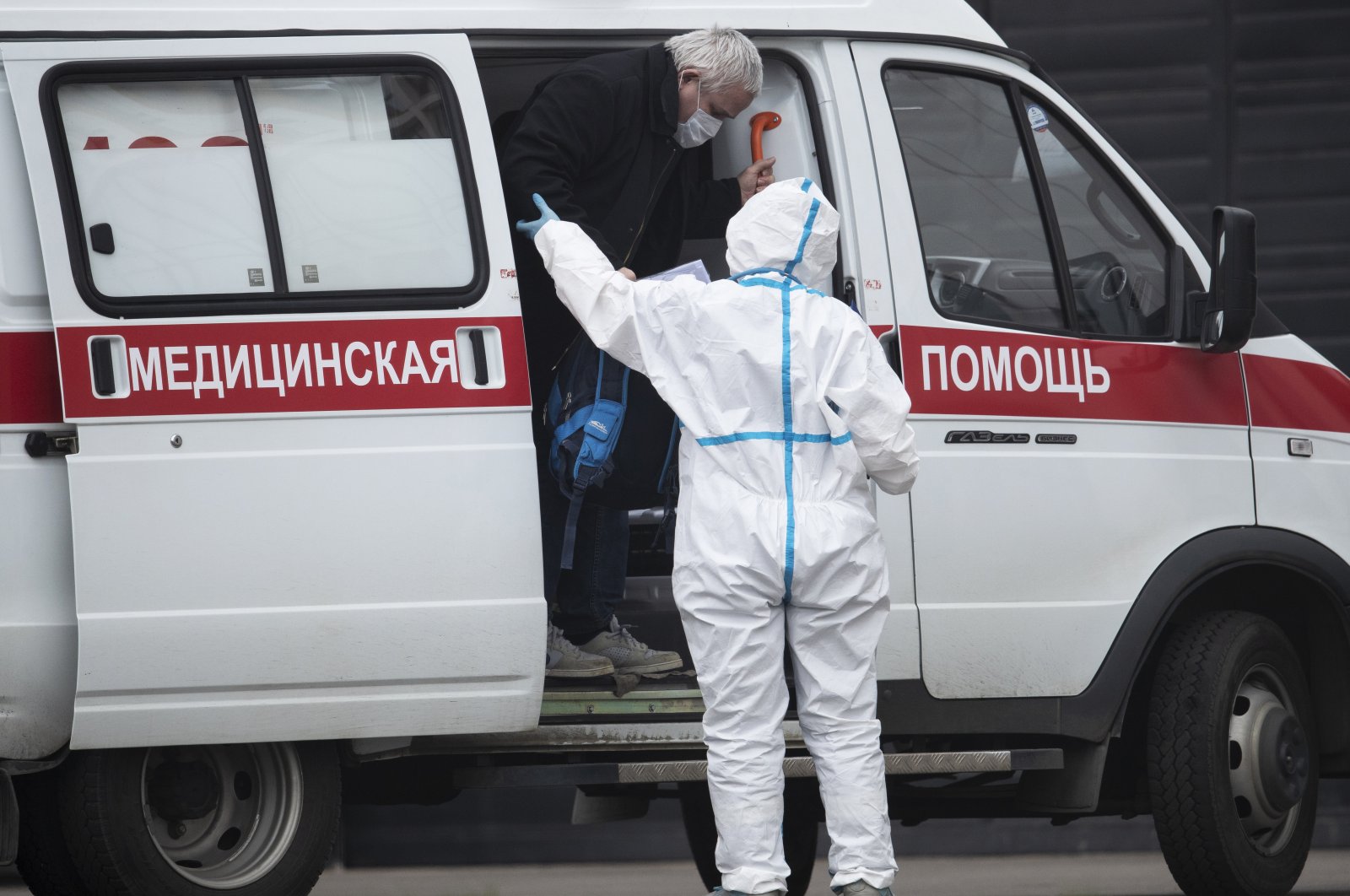 In this April 27, 2020, photo, a medical worker wearing protective gear helps a man, suspected of having the coronavirus infection, to get out from an ambulance at a hospital in Kommunarka, outside Moscow, Russia. (AP Photo)