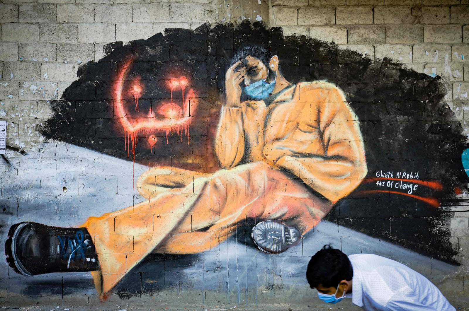 A youth, wearing a protective mask, walks past a mural reading "We are tired," Tripoli, Lebanon, April 28, 2020. (AFP Photo)