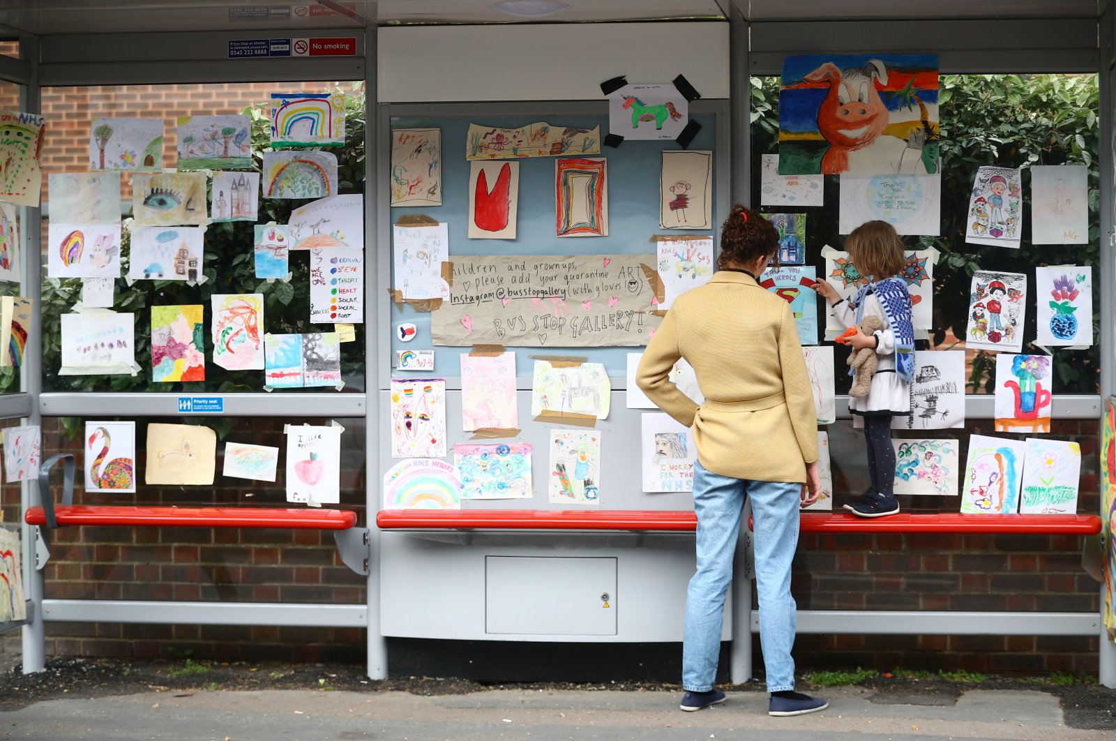 Sarah Lamarr and her 4-year-old daughter, Rosie, who started a "bus stop gallery" look at artwork at the bus stop following the outbreak of the coronavirus, London, Britain, April 27, 2020. (Reuters Photo)
