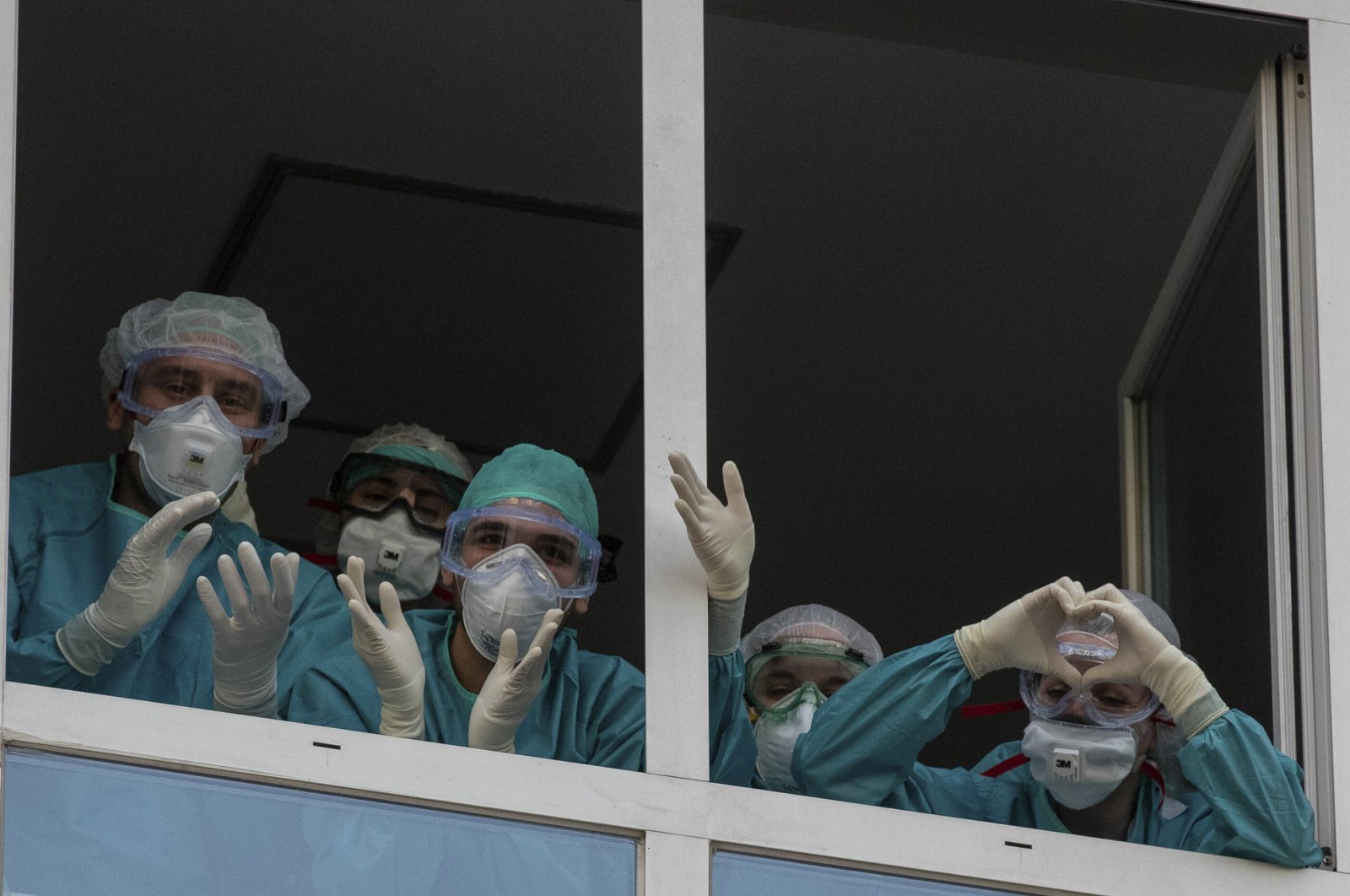 Health workers react as people applaud from their nearby houses in support of the medical staff, Madrid, April 15, 2020. (AP Photo)