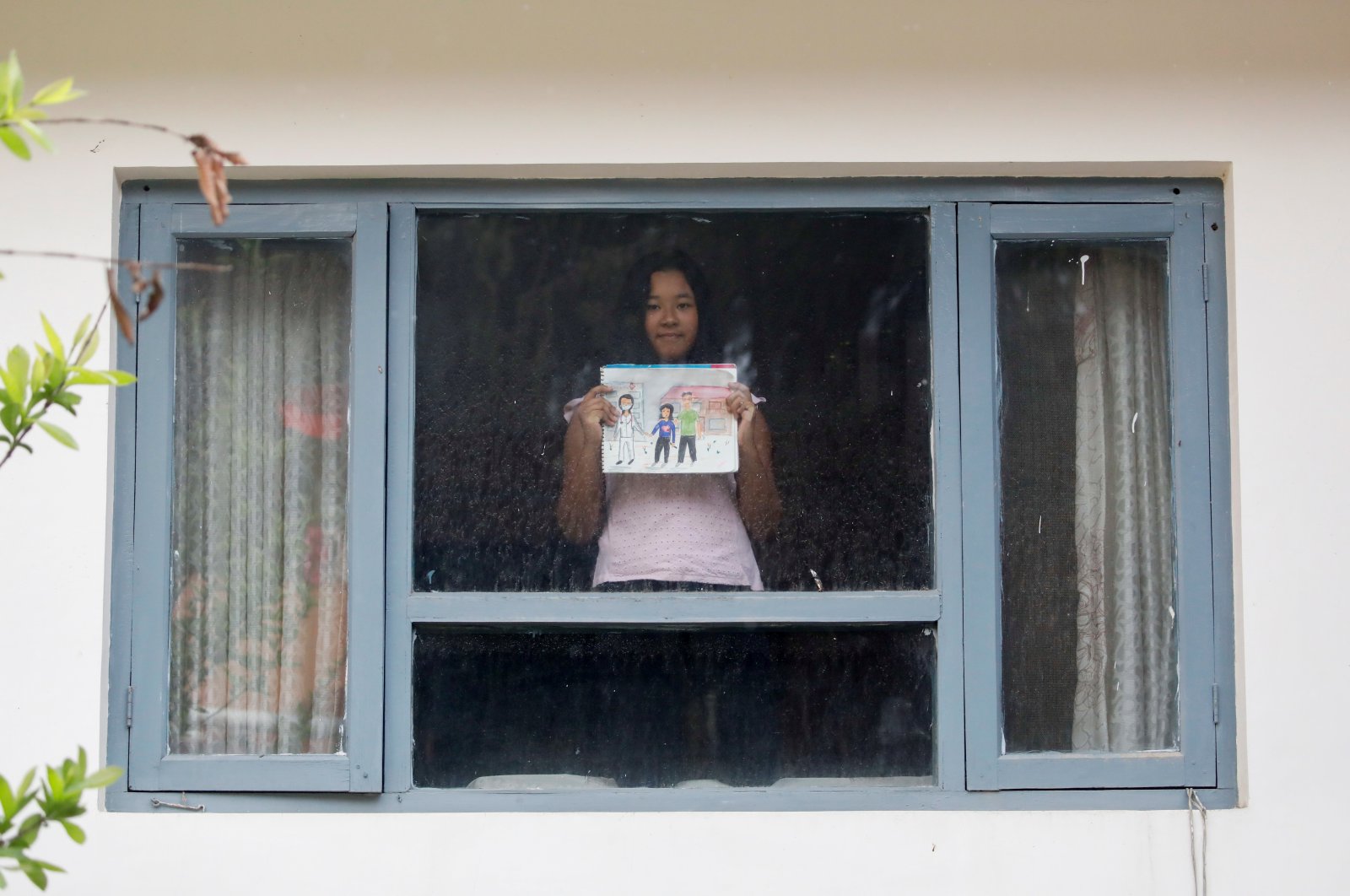 A girl poses for a photograph while holding a picture that she drew during the coronavirus outbreak, Kathmandu, Nepal, April 16, 2020. (REUTERS Photo)