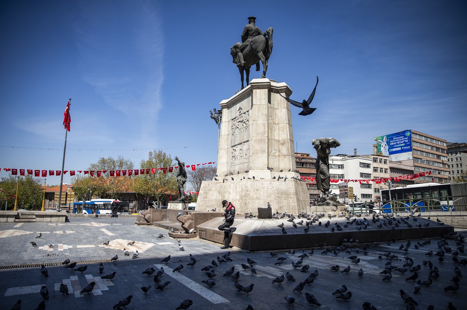 A police officer stands next to a statue at otherwise busy Ulus Square, in Ankara, Turkey, April 28, 2020. (AA Photo)