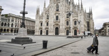 A man pulls his trolley past the Gothic cathedral in Milan during the coronavirus pandemic, Italy, April 27, 2020. (AP Photo)