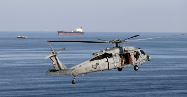This file photo shows MH60S helicopter hovers in the air with an oil tanker in the background as the USS John C. Stennis makes its way to the Gulf through the Strait of Hormuz, Dec. 21, 2018. (Reuters Photo)