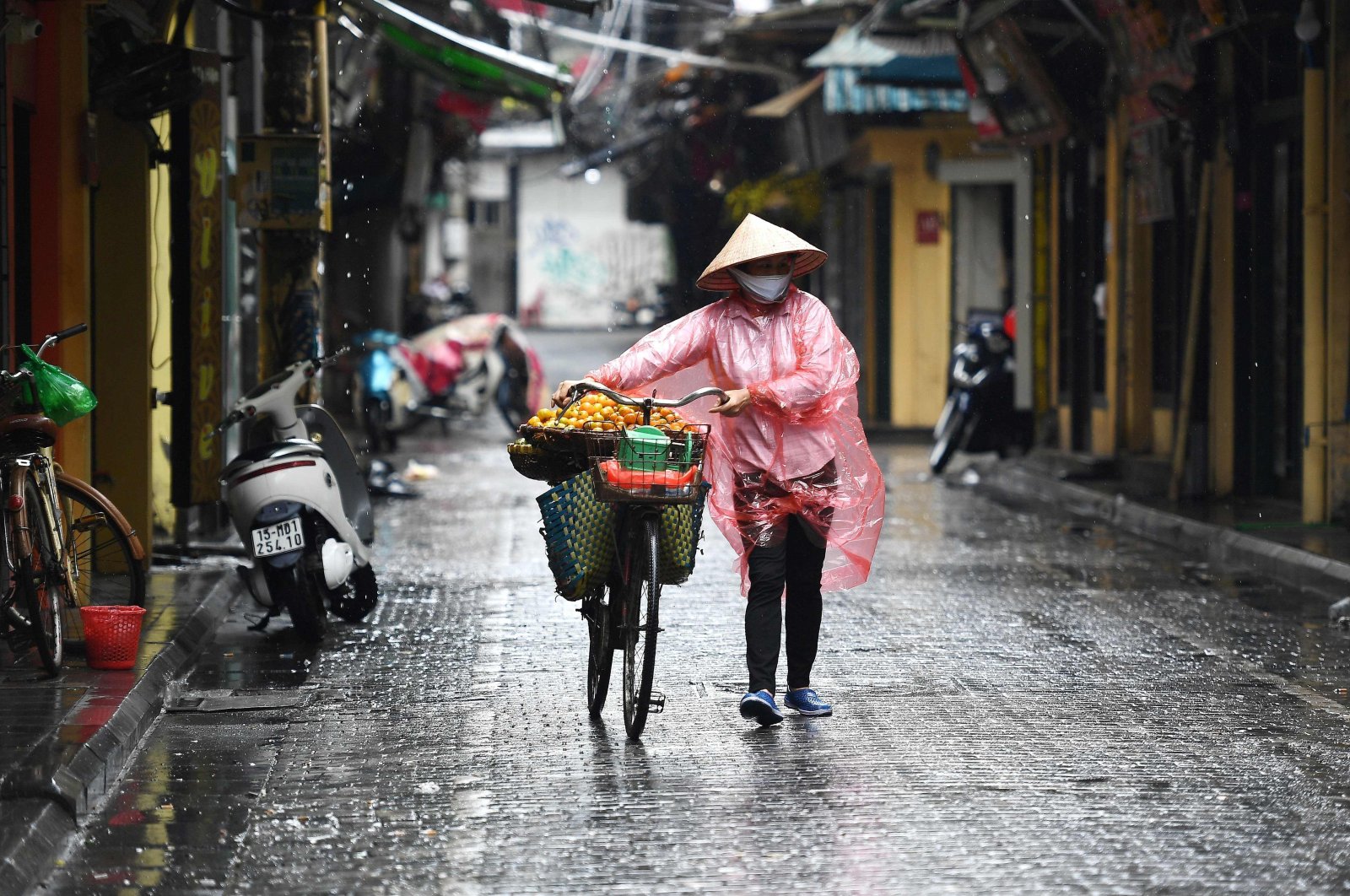 A fruit vendor wearing a face mask walks on a street in Hanoi, Vietnam, April 23, 2020. (AFP Photo)