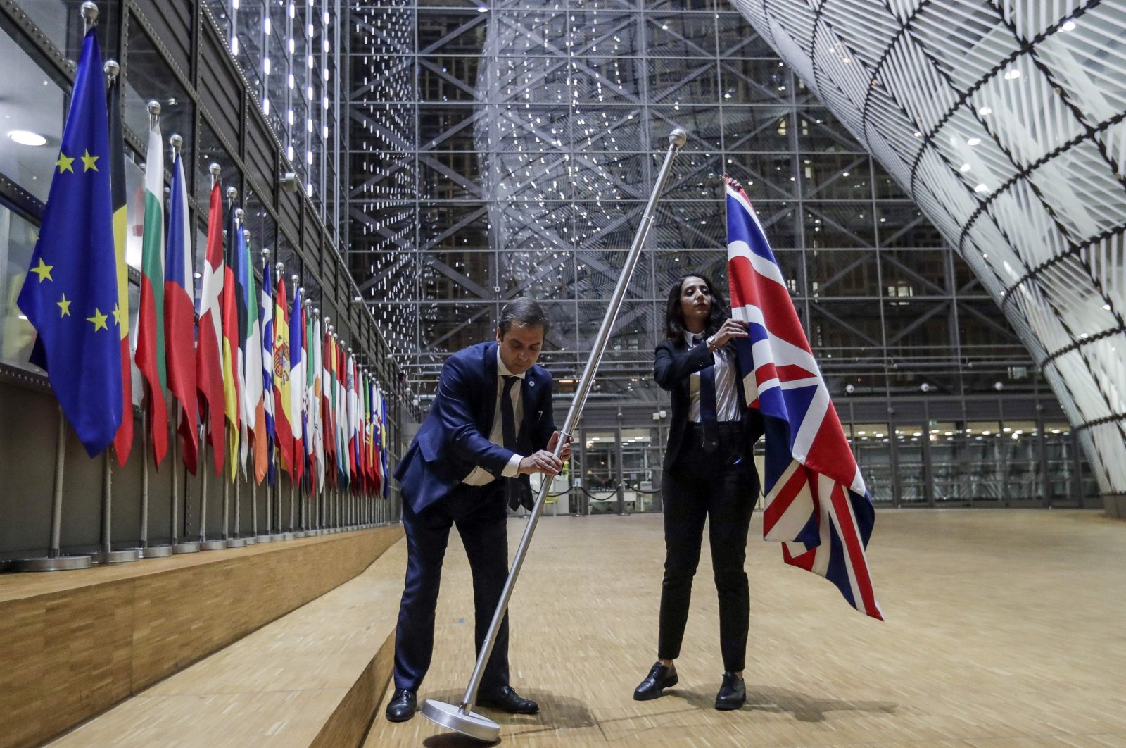 EU Council staff members remove the United Kingdom's flag from the European Council building on Brexit Day, Brussels, Jan. 31, 2020. (AFP Photo)