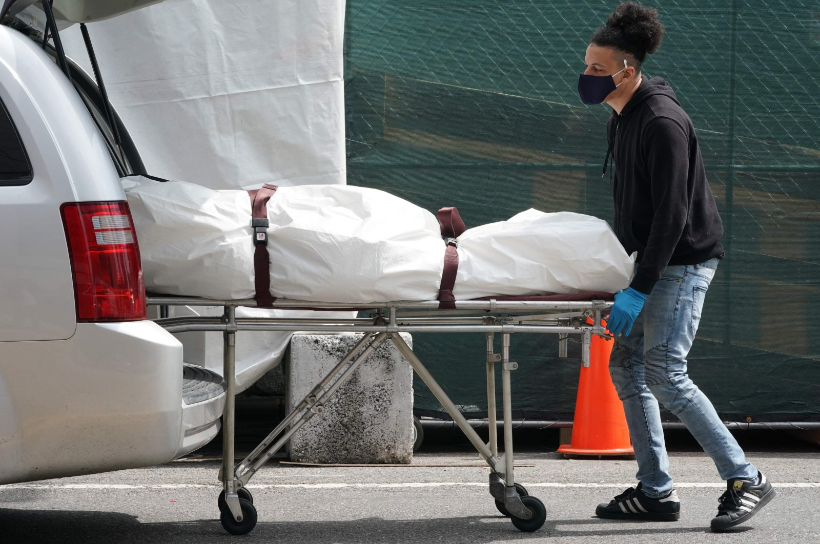 In this file photo taken on April 08, 2020 a body is moved from a refrigeration truck serving as a temporary morgue to a vehicle at the Brooklyn Hospital Center, in the Borough of Brooklyn  in New York. (AFP Photo)