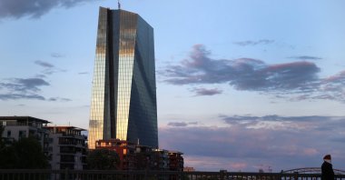 A woman wearing a protective mask walks past the headquarters of the European Central Bank (ECB) at sunset in Frankfurt, Germany, April 29, 2020. (Reuters Photo)