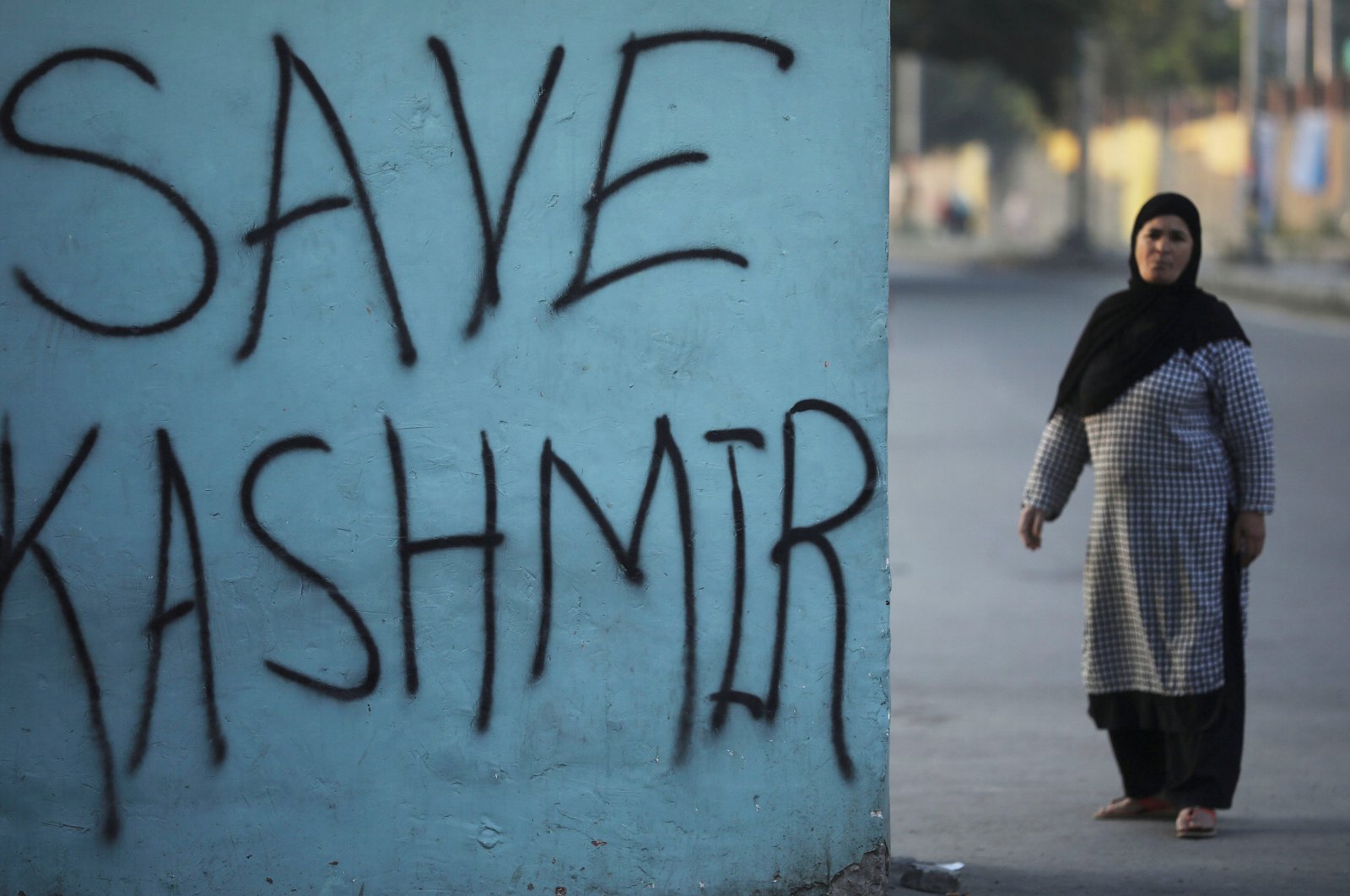 A Kashmiri woman stands next to graffiti written on a wall during restrictions, Srinagar, Jammu and Kashmir, Sept. 15, 2019. (Reuters Photo)