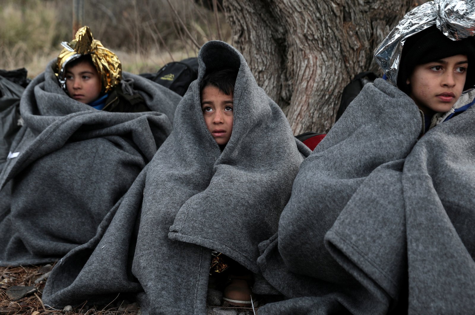 Children are covered with blankets and thermal blankets after migrants from Afghanistan arrived on a dinghy on a beach near the village of Skala Sikamias on the island of Lesbos, Greece, Feb. 28, 2020. (REUTERS Photo)