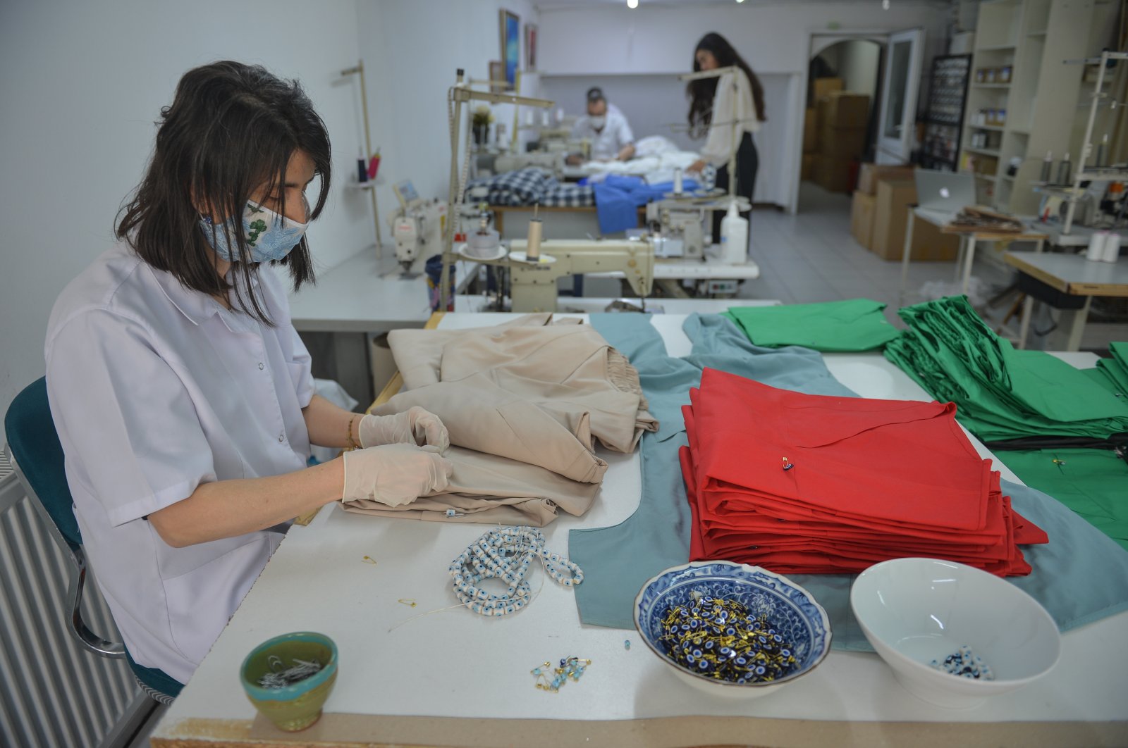 A worker puts small beads on scrubs at Aslı Filinta's workshop, in Istanbul, Turkey, April 30, 2020. (DHA Photo) 