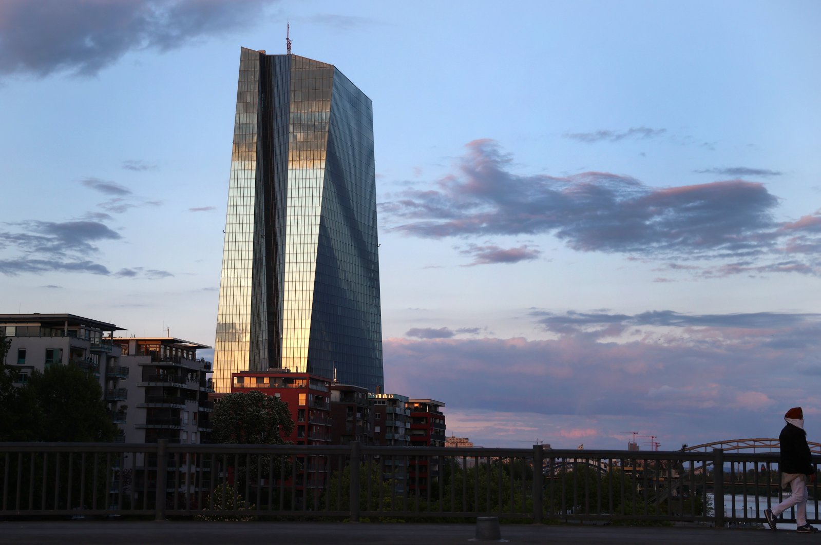 A woman wearing a protective mask walks past the headquarters of the European Central Bank (ECB) at sunset in Frankfurt, Germany, April 29, 2020. (Reuters Photo)