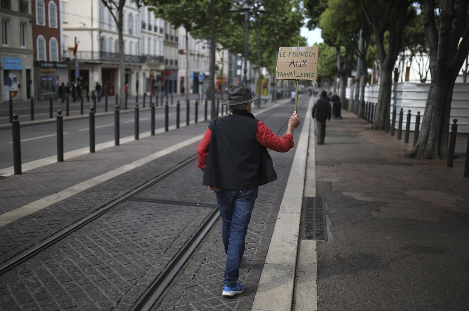 A lonely protester holds a poster reading "Power to workers," Marseille, May 1, 2020. (AP Photo)