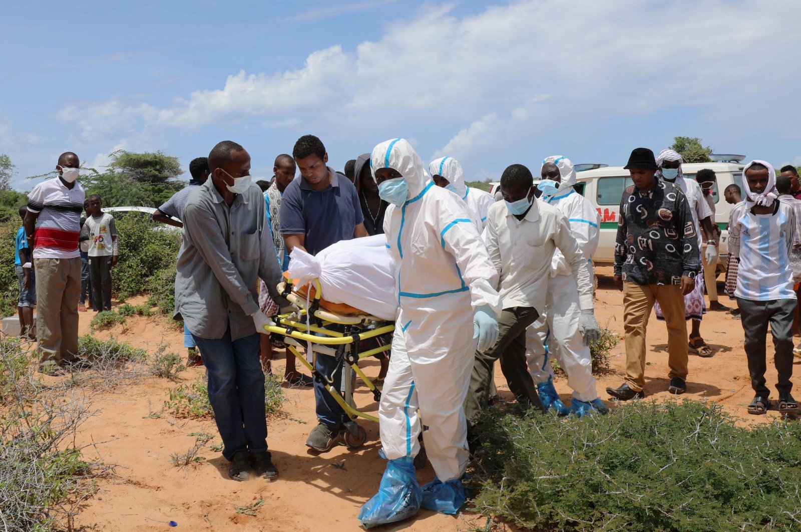 Somali workers in protective suits and civilians carry the body of a man suspected to have died of the coronavirus disease, for burial in Madina district outside of Mogadishu, Somalia April 30, 2020. REUTERS