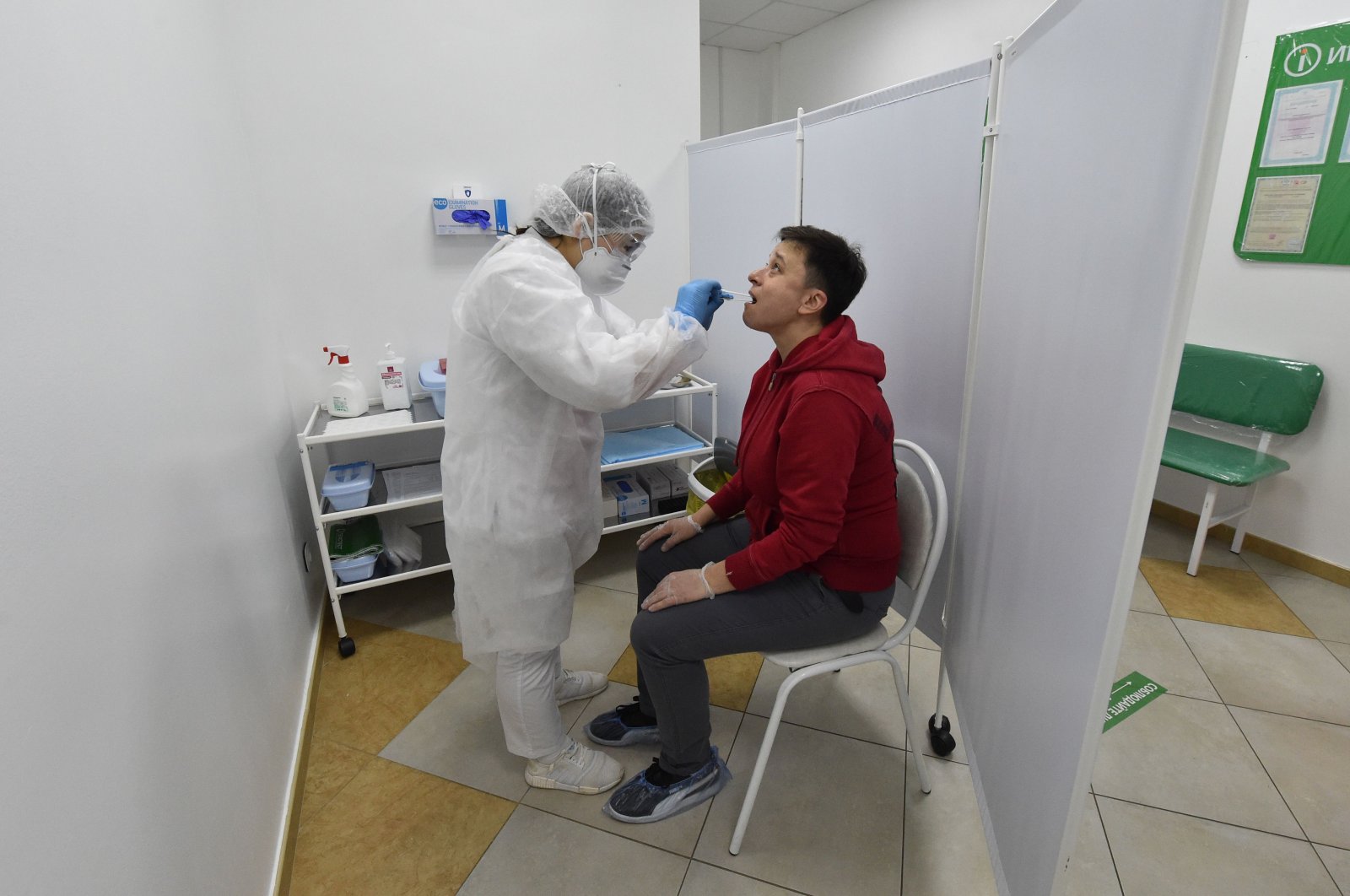 A medical staff member of Gemotest wearing protective gear, glasses and a face mask takes a saliva sample from a man at a drive-in COVID-19 testing facility in Moscow amid the COVID-19 pandemic, May 2, 2020. (AFP Photo)