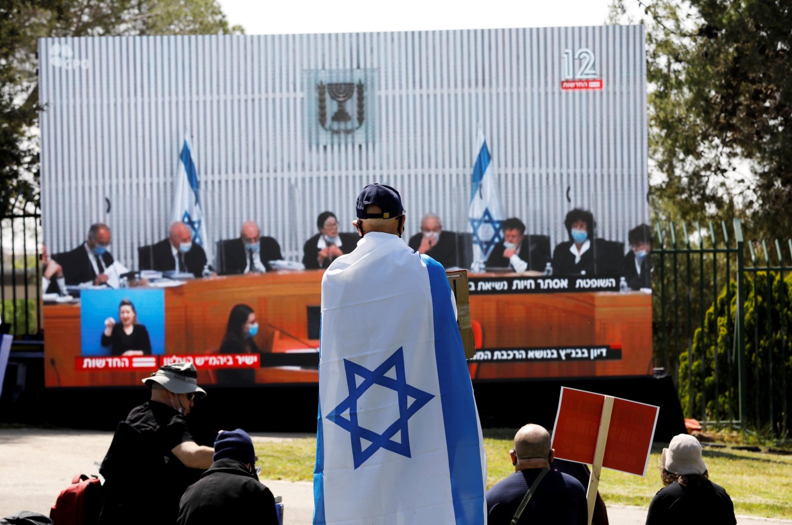 Israelis protest, in front of a placard with the photo of the High Court judges outside the Knesset against Prime minister Benjamin Netanyahu in Jerusalem, May 3, 2020. (Reuters Photo)