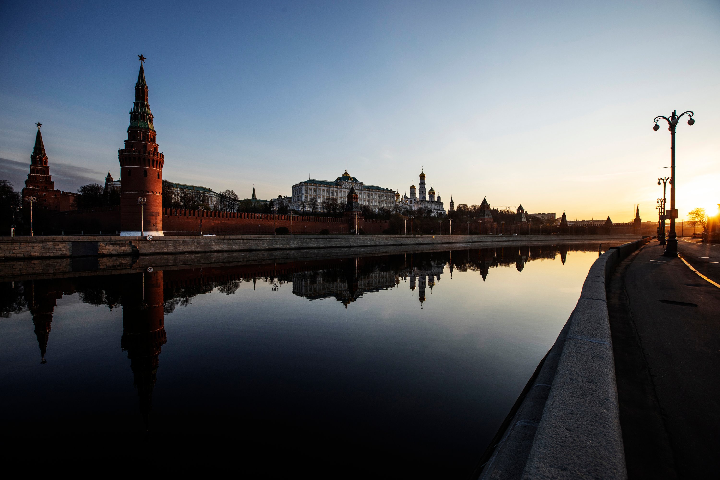 The Kremlin and its towers and churches are reflected in the Moscow River along a deserted embankment as the sun rises over Moscow, Russia, Monday, April 27, 2020. (AP Photo)